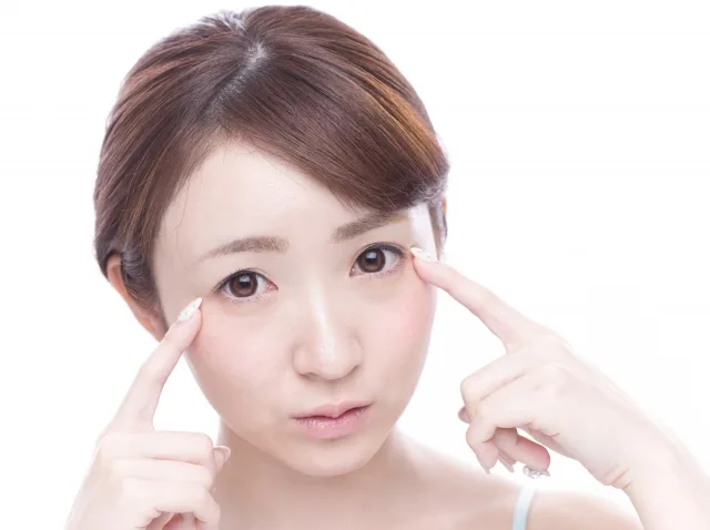 両指で目を示す女性