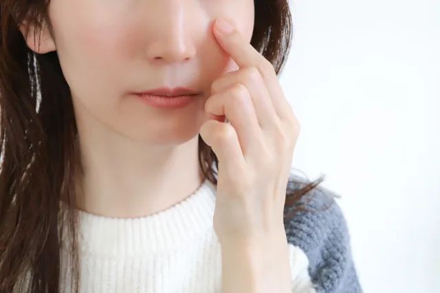 指で目を示す女性