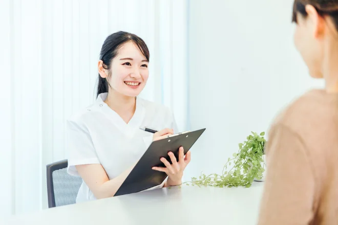 問診票を記入する看護師と患者